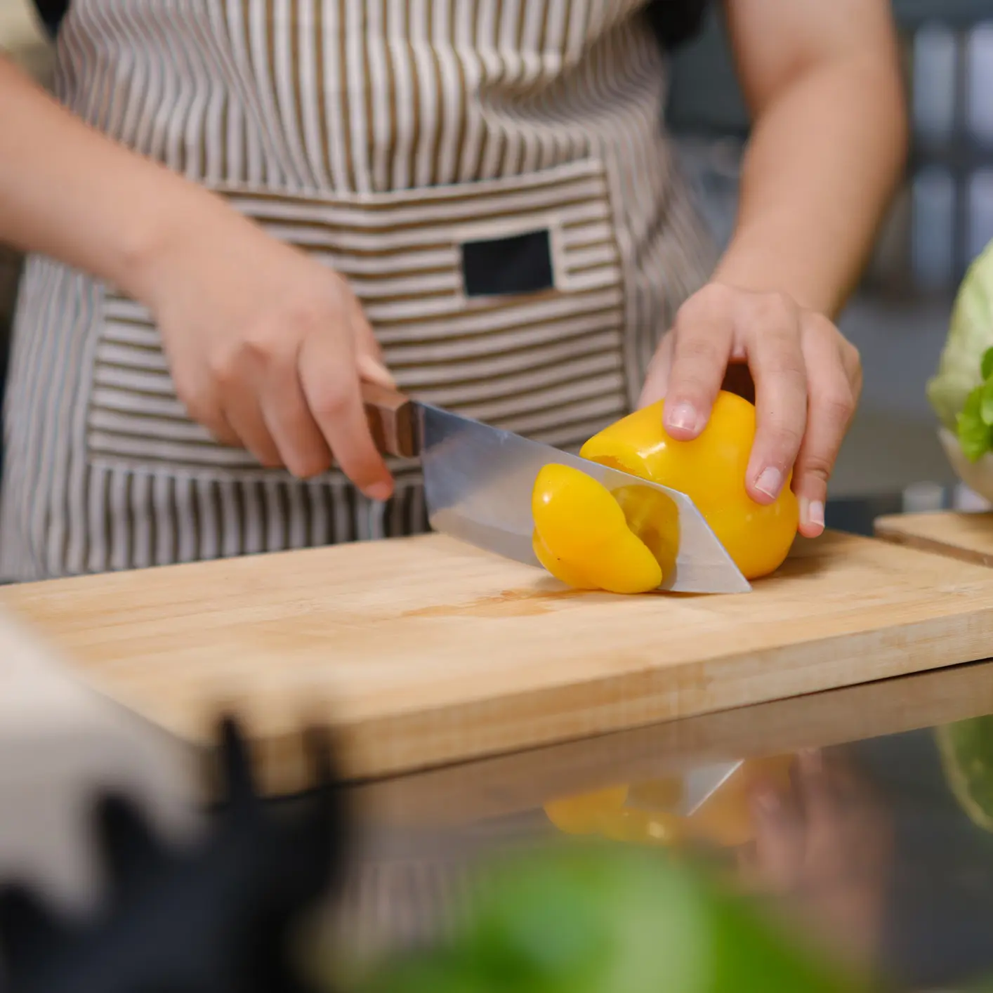 Slicing yellow bell pepper on cutting board