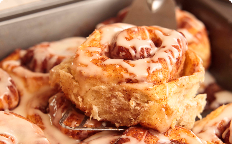 Iced cinnamon rolls in a baking tray.